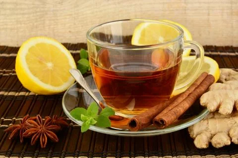 Ginger tea-ingwertee on brown mat with lemon,cinnamon,anise and mint on mat Stock Photos