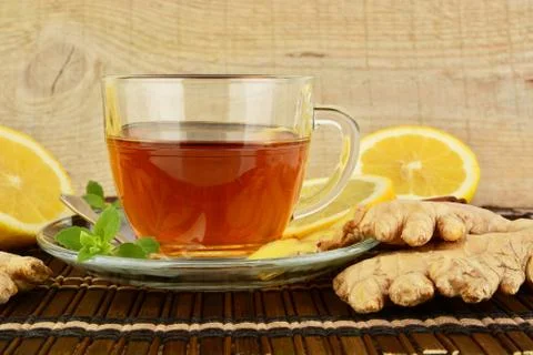 Ginger tea-ingwertee on brown mat with lemon and mint with wooden background Stock Photos