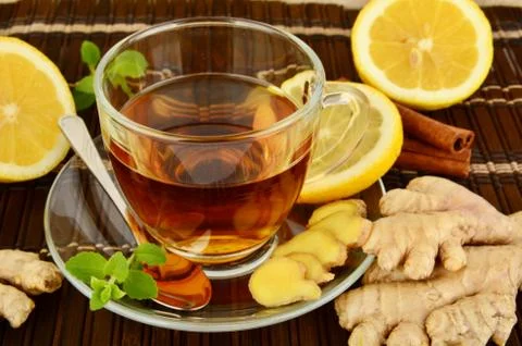 Ginger tea-ingwertee on brown mat with lemon,cinnamon and mint on mat Stock Photos