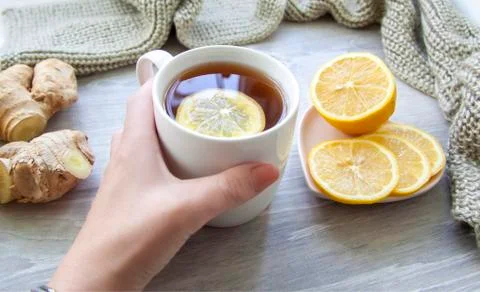 Ginger tea with lemon. A Cup of tea is held by a woman's hand. Season of cold Stock Photos