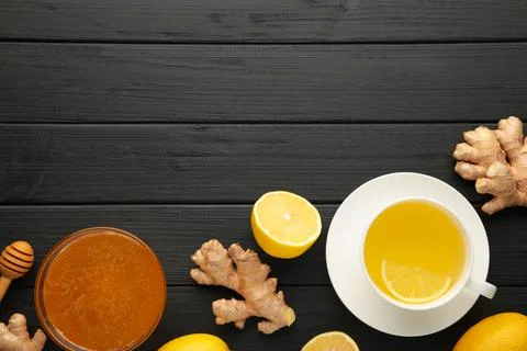 Ginger tea with lemon in a white cup on black background. Stock Photos