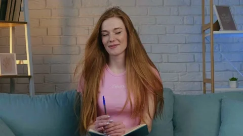 Ginger woman is smiling at camera while having a video call at home holding a Stock Footage 155753677