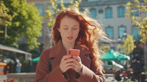 Ginger young female student using smartphone app messaging in city center. Poor Stock Footage 131124515