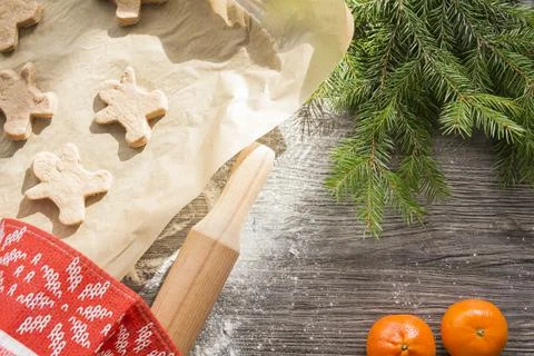 Gingerbread cakes in the form of men and houses lie on a baking sheet, on bak Stock Photos
