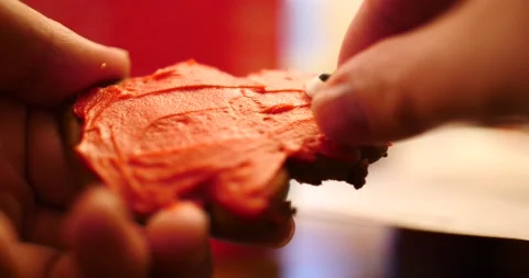 Gingerbread cookie covered in red frosting being decorated close up Stock Footage 217361042