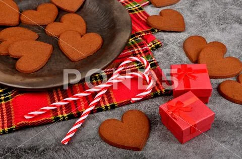 Gingerbread heart on a black clay plate and Christmas decorations .Gray concrete Stock Photos