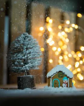 Gingerbread house and Christmas tree over wooden background with blurred lights Foto stock