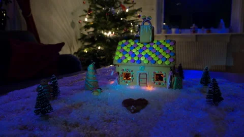 A gingerbread house on a table in a Christmas decorated home. Video stock 220304793