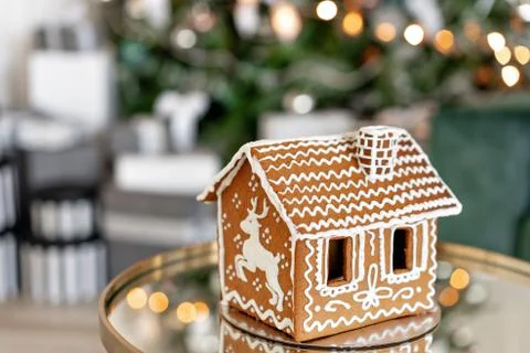 Gingerbread house on table. Defocused lights of Christmas tree. Morning in the Stock Photos