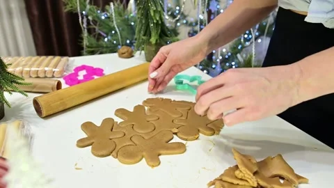 Gingerbread man figurine being made by a girl with Christmas tree in view Stock Footage 344820828