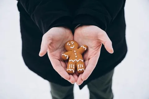 Gingerbread man in the hands of a man against a background of snow, close-up. Stock Photos