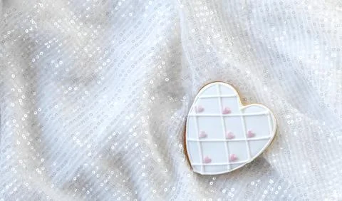Gingerbread in the shape of a heart on a white background with sequins Foto stock