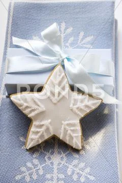 Gingerbread Star With White Icing In Front Of Gift