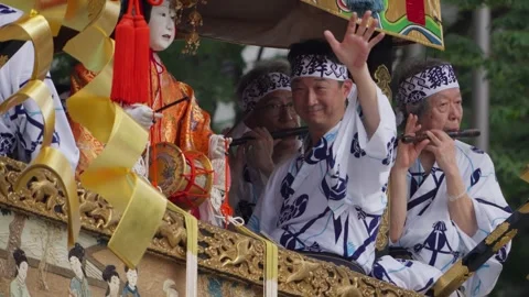 Gion Matsuri Participant Waves to Crowd as Musician Plays Flute on Hoko Float Stock Footage 346789181