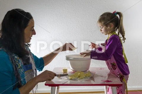 Girl 3 years and her mother baking mixing ingredients in a white bowl Stock Photos