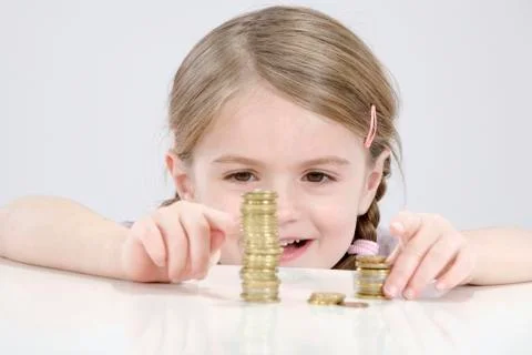 Girl (4-5) counting stack of coins 스톡 사진