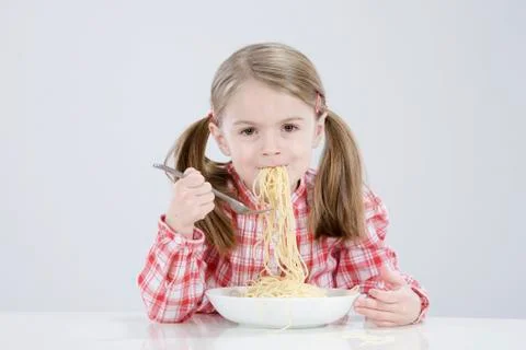 Girl (4-5) eating spagetti, smiling, portrait Stock Photos