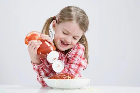 Girl (4-5) pouring ketchup on spagetti Stock Photos