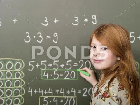 Girl (6-7) Standing And Writing On Blackboard, Portrait, Close-Up