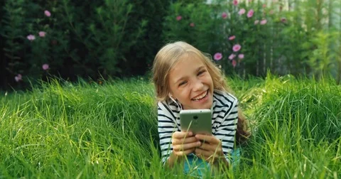 Girl 9 years old using cell phone and listening music in earphones Vídeos de archivo 80070465