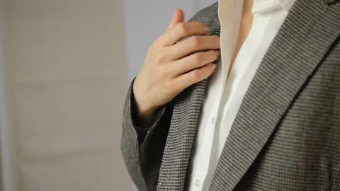 The girl adjusts her jacket and collar. White shirt, gray pajama top. Close-up.  Stock Footage 148990180
