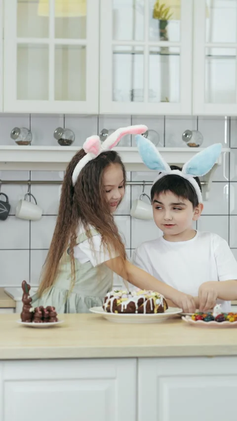 A girl and boy decorates an Easter cake with decorative eggs. Stock Footage 303621696