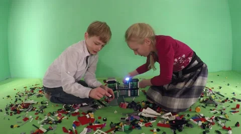 Girl and boy playing constructor. Green background. Video stock 59661490