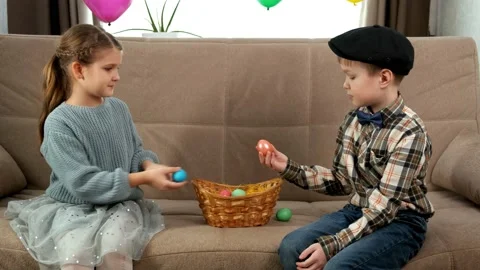 A girl and a boy take Easter eggs out of a wicker basket and exchange them Stock Footage 169817925
