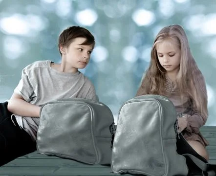 Girl and boy with travel backpacks sitting on the floor against the background Stock Photos