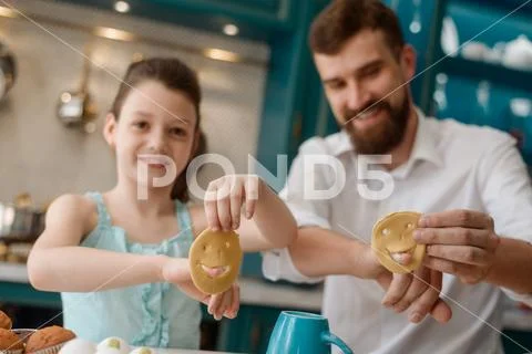 Girl and dad play with dough in kitchen, while making cookies Stock Photos