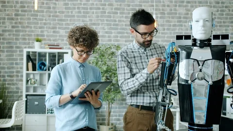 Girl and guy testing robot functions using modern equipment tablet in office 動画素材 119818140