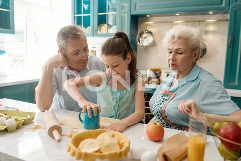 Girl and her grandparents baking at a kitchen Stock Photos