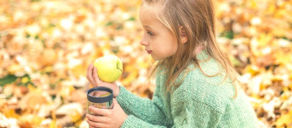 Girl with apple and drink in autumn park Stock Photos