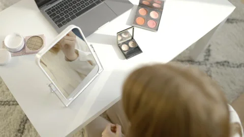 Girl applying face blush in front of mirror, recording beauty tutorial, top-view Stock Footage 152036022