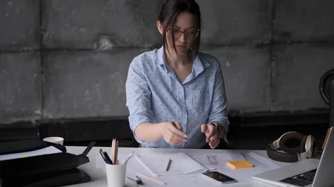 Girl architect uses a smartphone while sitting at the table in the office. Stock Footage 108615096
