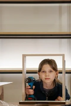 Girl assembling frame with drill pointed downwards Stock Photos