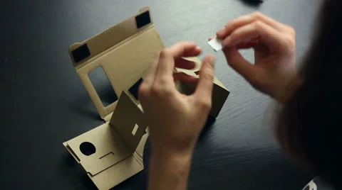 Girl assembling a Virtual Reality cardboard glasses Stock Footage 66646668