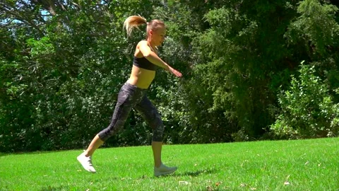 Girl athlete does physical exercise on green grass outdoors Stock Footage 131955535