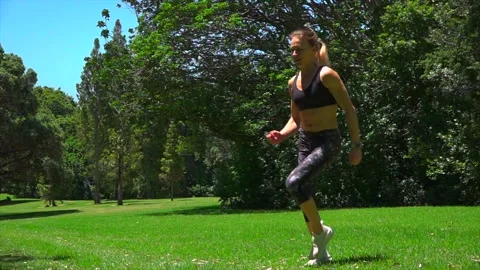 Girl athlete does physical exercise on green grass outdoors in the park Stock Footage 131955650