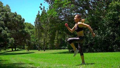 Girl athlete does physical exercise on green grass in the forest in new zealand Stock Footage 131955658