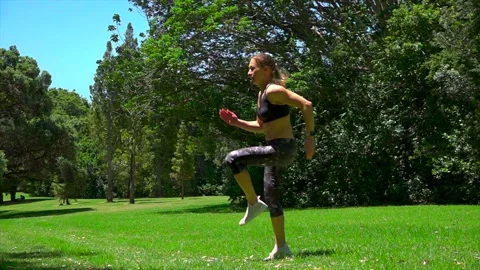 Girl athlete does physical exercise on green grass in the forest in new zealand Stock Footage 131955700