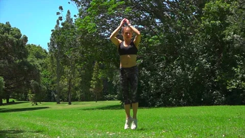 Girl athlete does physical exercise on green grass in the forest in new zealand Stock Footage 131955762