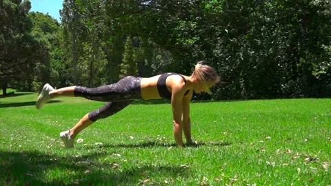 Girl athlete does physical exercise on green grass in the forest in new zealand Stock-Footage 131955896