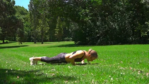 Girl athlete does physical exercise on green grass in the forest in new zealand Stock Footage 131955922
