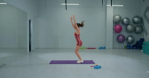 Girl athlete performs a burpee exercise in a modern gym setting during daytime Stock Footage 311211676