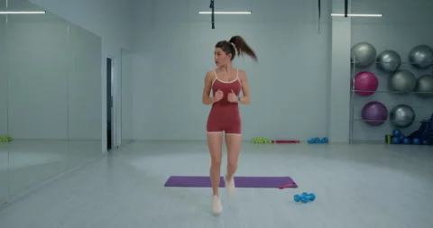 Girl athlete practicing butt kicks in a gym during a fitness session focusing on Stock Footage 311212287