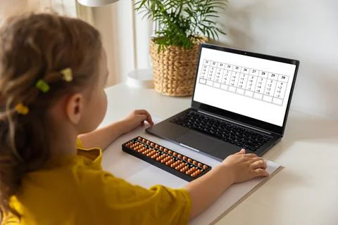 A girl from the back is engaged in mental arithmetic on the abacus online on a Stock Photos