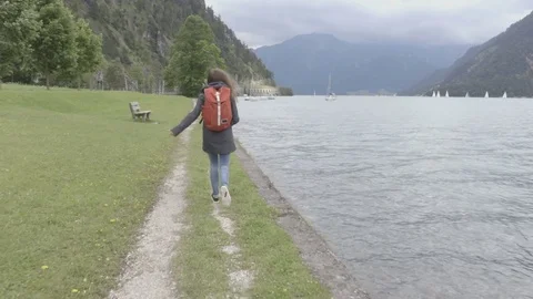 Girl with the back-pack is running next to the lake Stock Footage 81935667