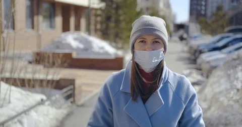 Girl on background of empty street, pretty lady in coat, mask, stands in street Stock Footage 129367643