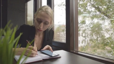 The girl on the background of the window, writing at a table Stock Footage 98007071